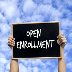 person holding up open enrollment sign over blue sky