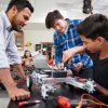 high school teacher with two students who are building a robotic vehicle