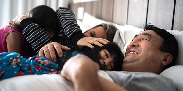Family piled in bed after waking up in the morning