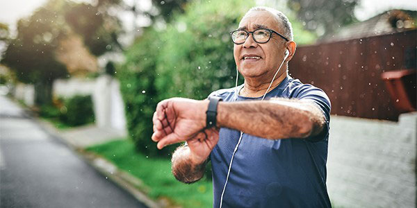 man exercising outdoors and checking his fitness tracker