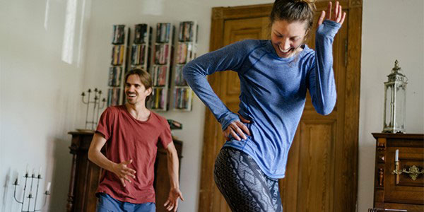 woman and man smiling while exercising at home
